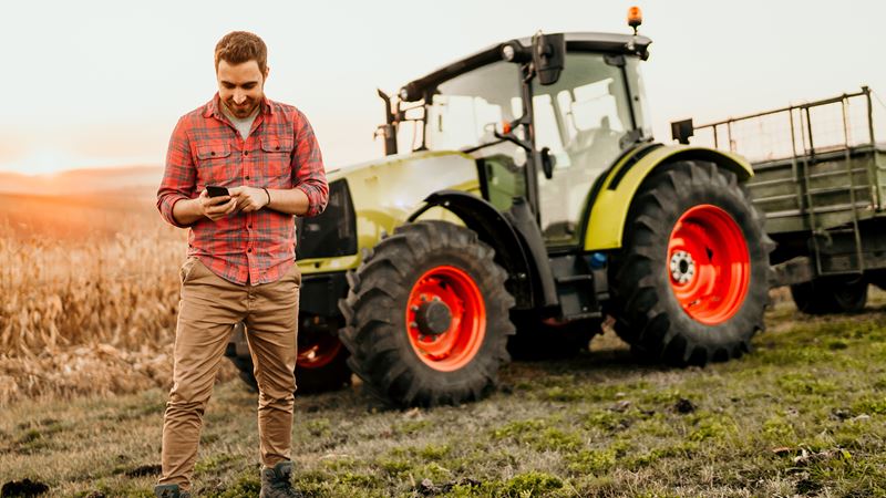 Man on cell phone with tractor in background